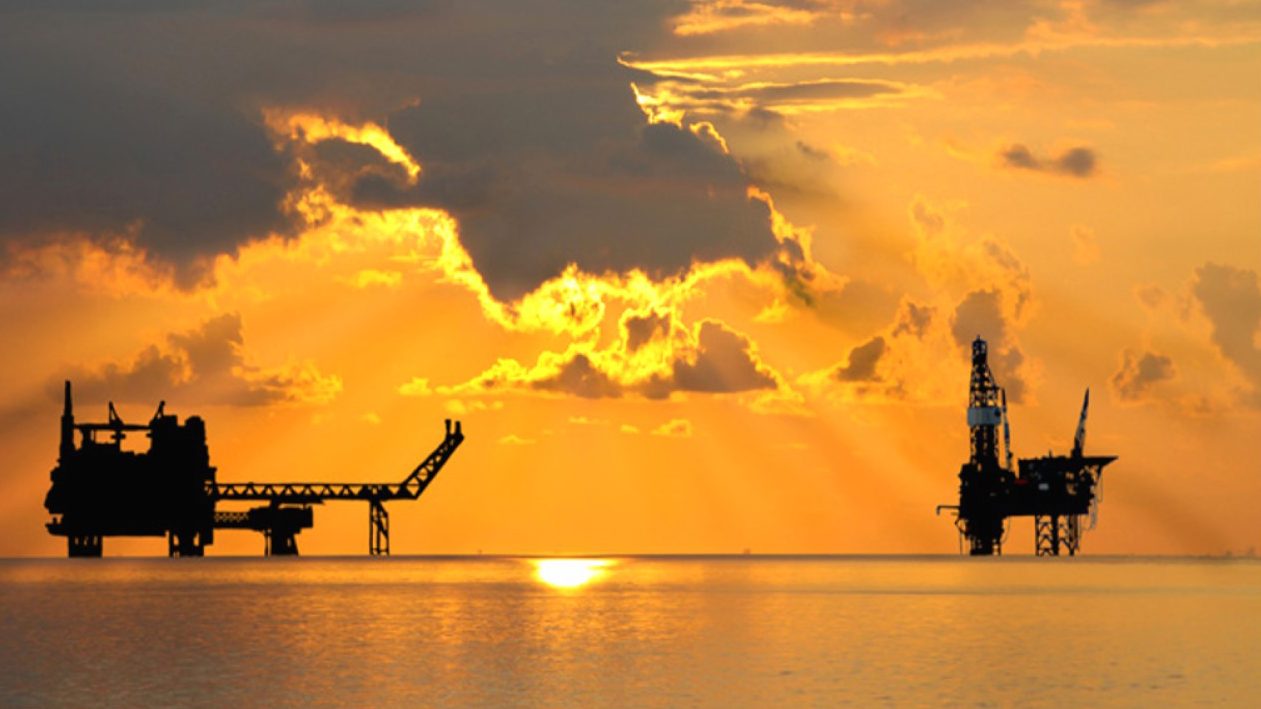 Offshore oil and gas platforms silhouetted at sunset